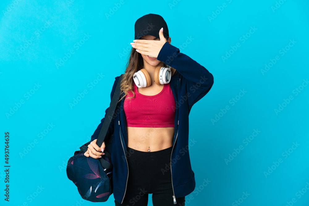 Young sport woman with sport bag isolated on blue background covering eyes by hands. Do not want to see something Young sport woman with sport bag isolated on blue background covering eyes by hands. Do not want to see something