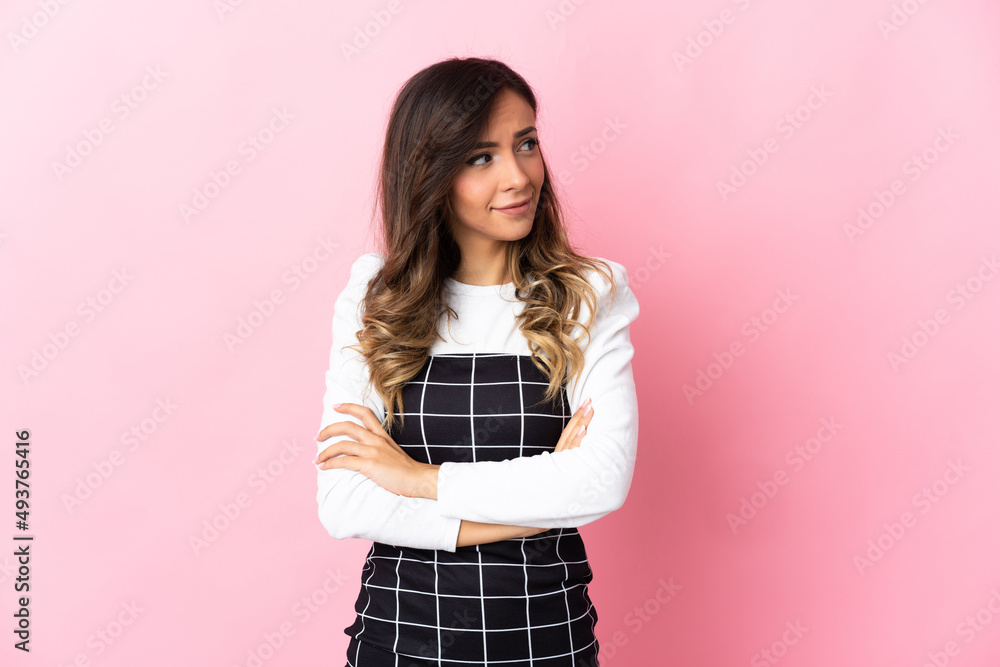 Young caucasian woman isolated on pink background making doubts gesture looking side Young caucasian woman isolated on pink background making doubts gesture looking side