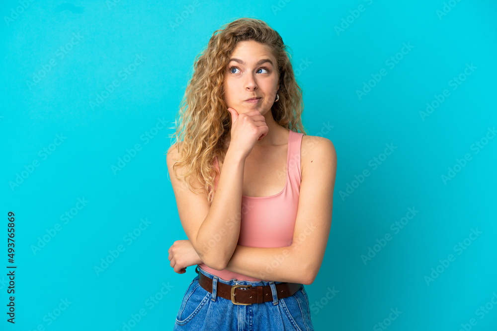 Young blonde woman isolated on blue background thinking an idea while looking up Young blonde woman isolated on blue background thinking an idea while looking up