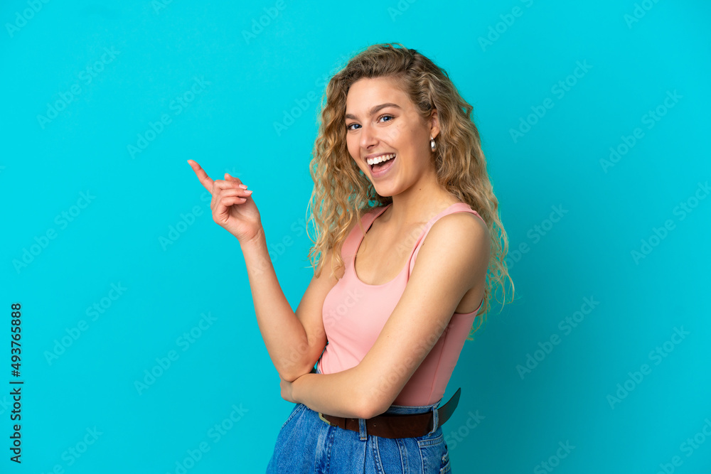 Young blonde woman isolated on blue background pointing finger to the side Young blonde woman isolated on blue background pointing finger to the side
