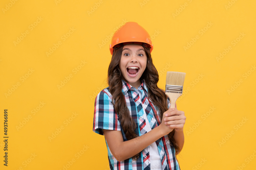 amazed kid with curly hair in construction helmet hold painting brush, renovator amazed kid with curly hair in construction helmet hold painting brush, renovator