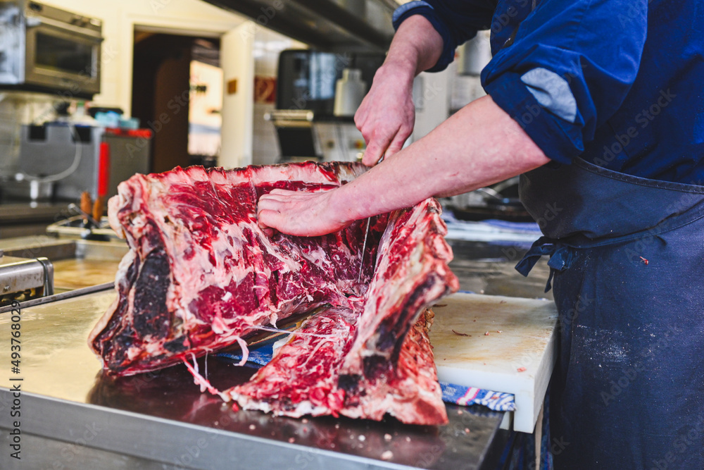 Koch präpariert schneidet Dry Aged Fleisch auseinander in einer Großküche im Restaurant 
