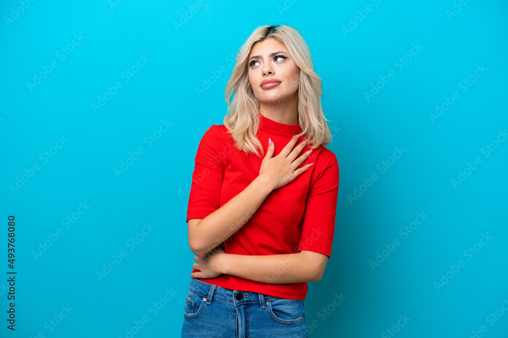 Young Russian woman isolated on blue background looking up while smiling Young Russian woman isolated on blue background looking up while smiling