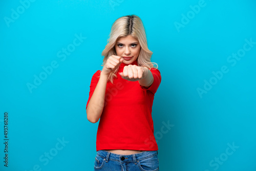 Young Russian woman isolated on blue background with fighting gesture