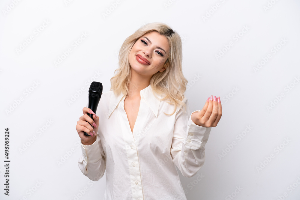 Young singer woman picking up a microphone isolated on white background making money gesture Young singer woman picking up a microphone isolated on white background making money gesture