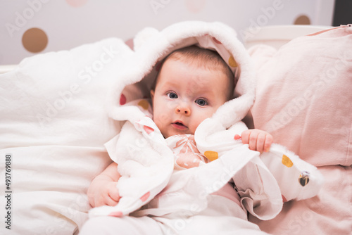 Baby girl, 5 month old, laying in bed, portrait of a toddler