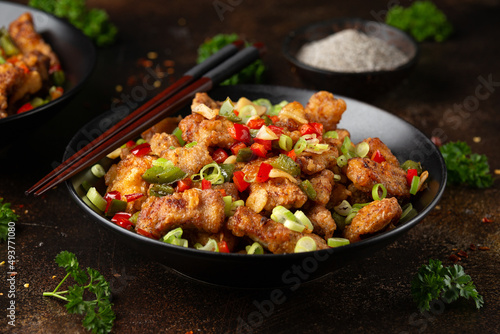 Stir fry salt and pepper pork loin with herbs in black bowl. Asian food