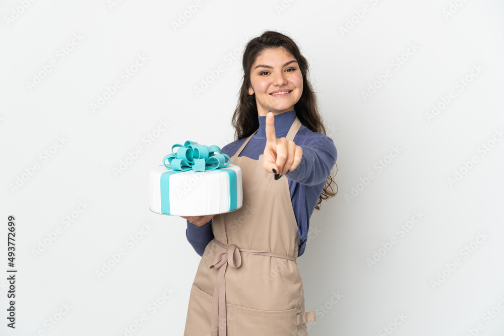 Pastry Russian chef holding a big cake isolated on white background showing and lifting a finger Pastry Russian chef holding a big cake isolated on white background showing and lifting a finger