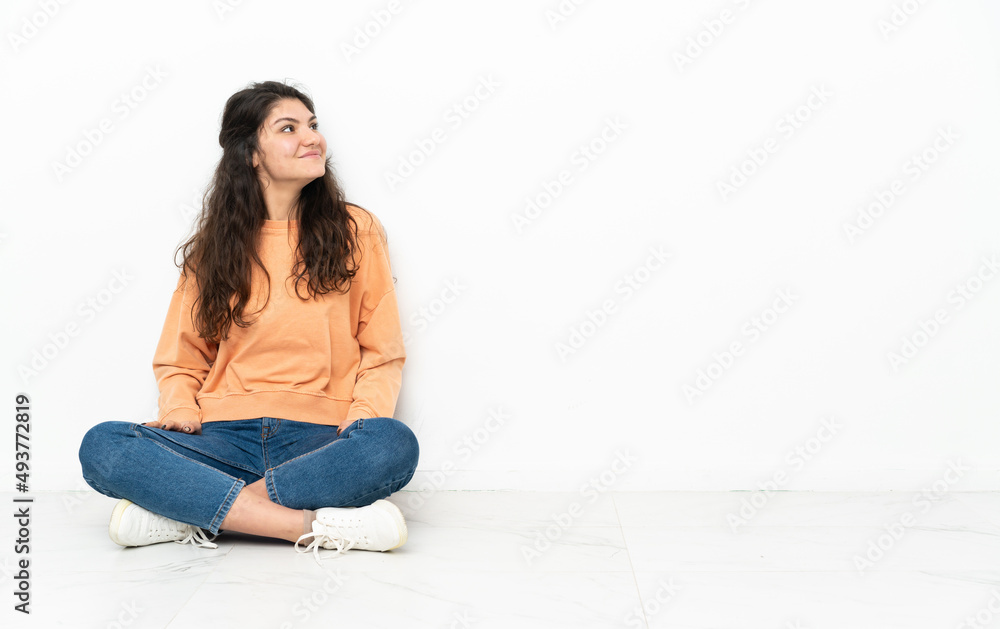 Teenager Russian girl sitting on the floor thinking an idea while looking up Teenager Russian girl sitting on the floor thinking an idea while looking up