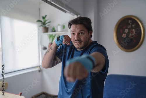 hombre con camiseta azul y cintas elásticas en las manos practicando deporte en casa