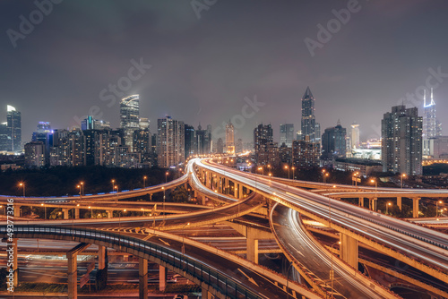 Urban overpasses with lights on at night and the urban background in the distance