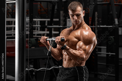 Fotobehang Muscular man in gym doing exercises for biceps, working out