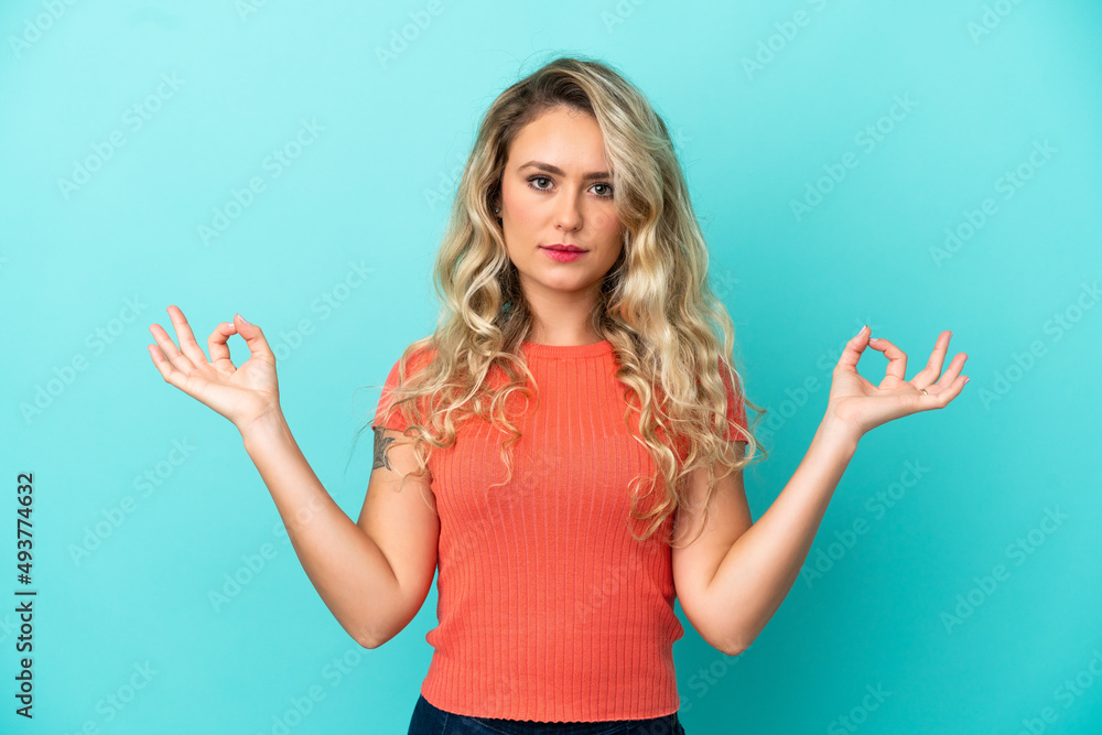 Fototapeta premium Young Brazilian woman isolated on blue background in zen pose