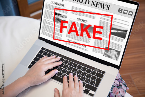 female hands laptop keyboard with world news and word fake