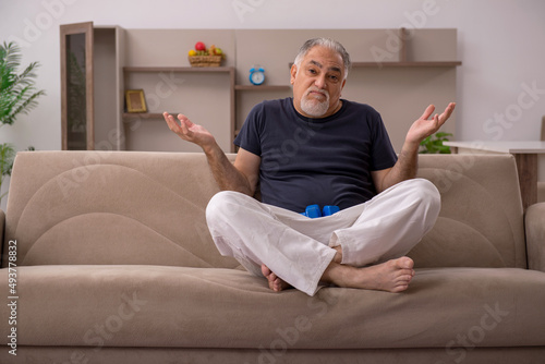 Old man doing sport exercises at home