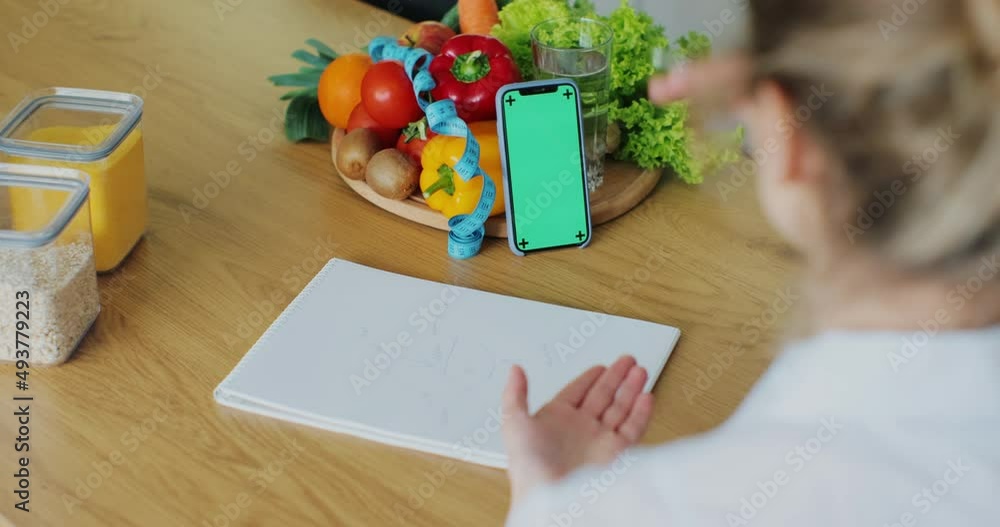 Nutritionist talking on video chat using smartphone with green screen