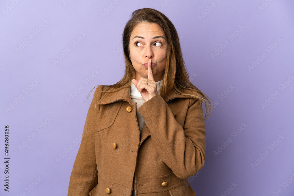 Middle age Brazilian woman isolated on purple background showing a sign of silence gesture putting finger in mouth Middle age Brazilian woman isolated on purple background showing a sign of silence gesture putting finger in mouth