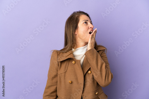 Middle age Brazilian woman isolated on purple background yawning and covering wide open mouth with hand