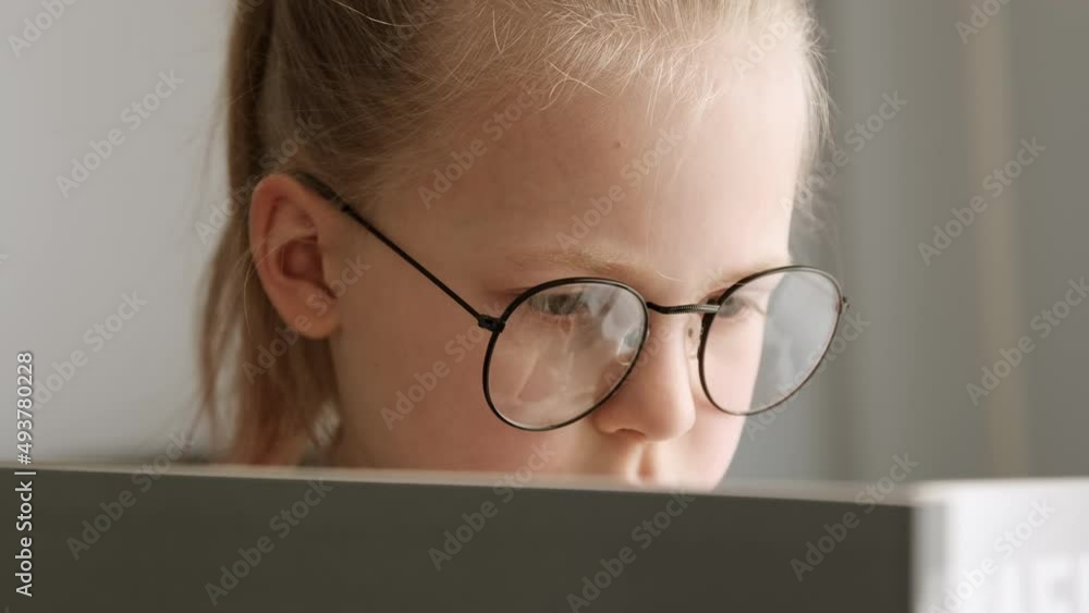 Little child clever girl reading a book in glasses after school, kid doing homework lessons, distance education and children's leisure and hobbies. Little child clever girl reading a book in glasses after school, kid doing homework lessons, distance education and children's leisure and hobbies.