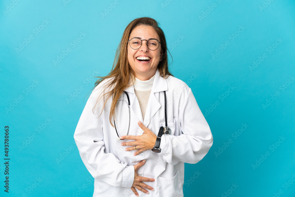 Middle age Brazilian doctor woman isolated on blue background smiling a lot Middle age Brazilian doctor woman isolated on blue background smiling a lot