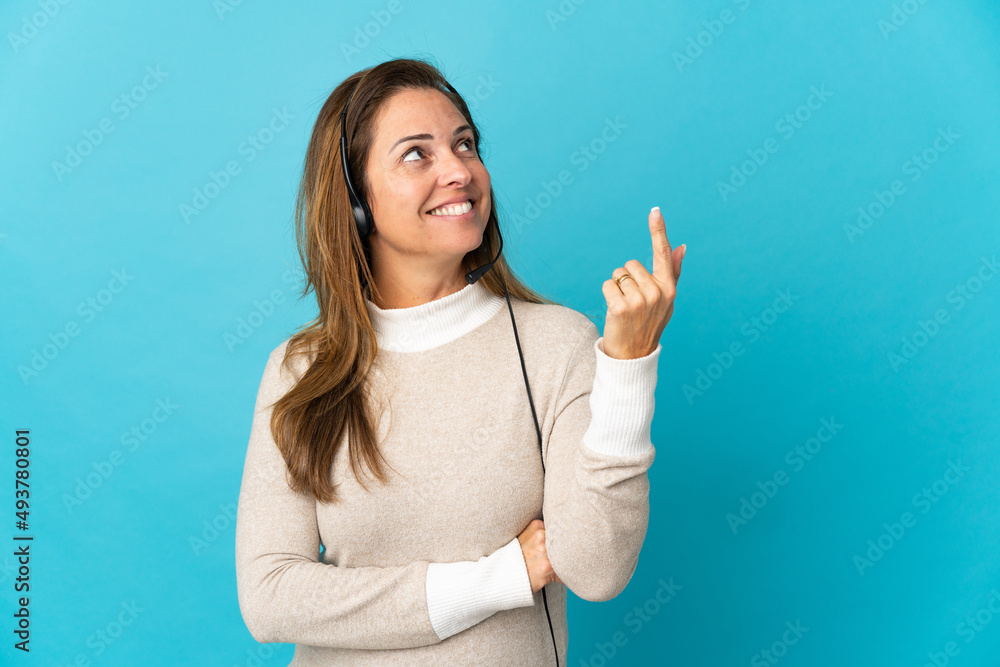 Young telemarketer woman over isolated blue background pointing up a great idea Young telemarketer woman over isolated blue background pointing up a great idea