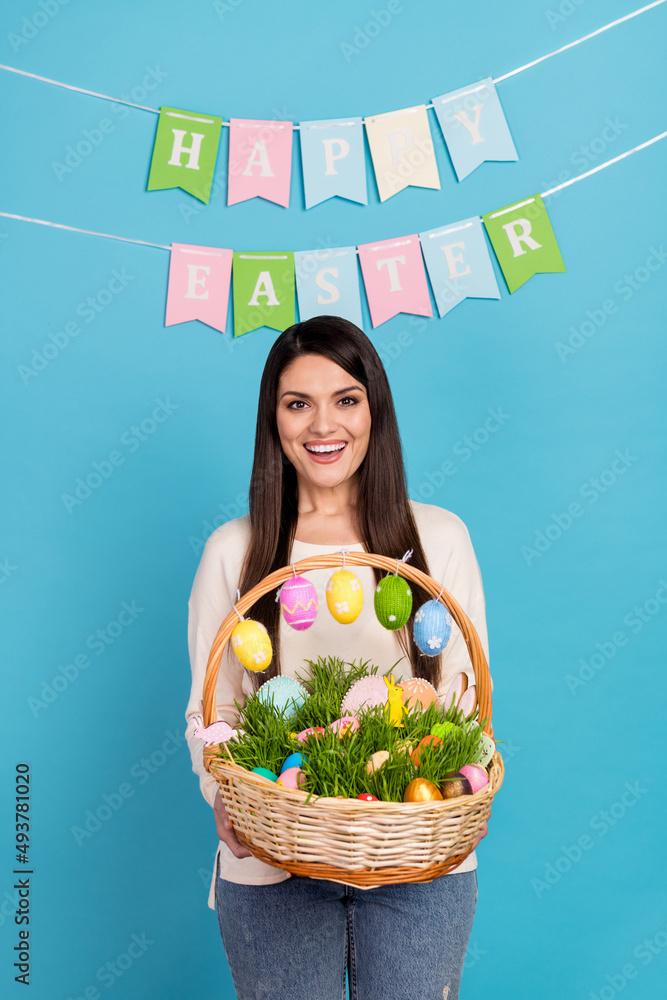 Photo of young excited woman hold basket eggs festive hang flags isolated over blue color background Photo of young excited woman hold basket eggs festive hang flags isolated over blue color background