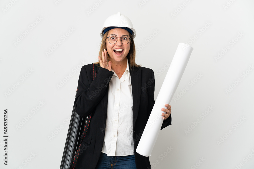 Middle age architect woman with helmet and holding blueprints over isolated background with surprise and shocked facial expression Middle age architect woman with helmet and holding blueprints over isolated background with surprise and shocked facial expression