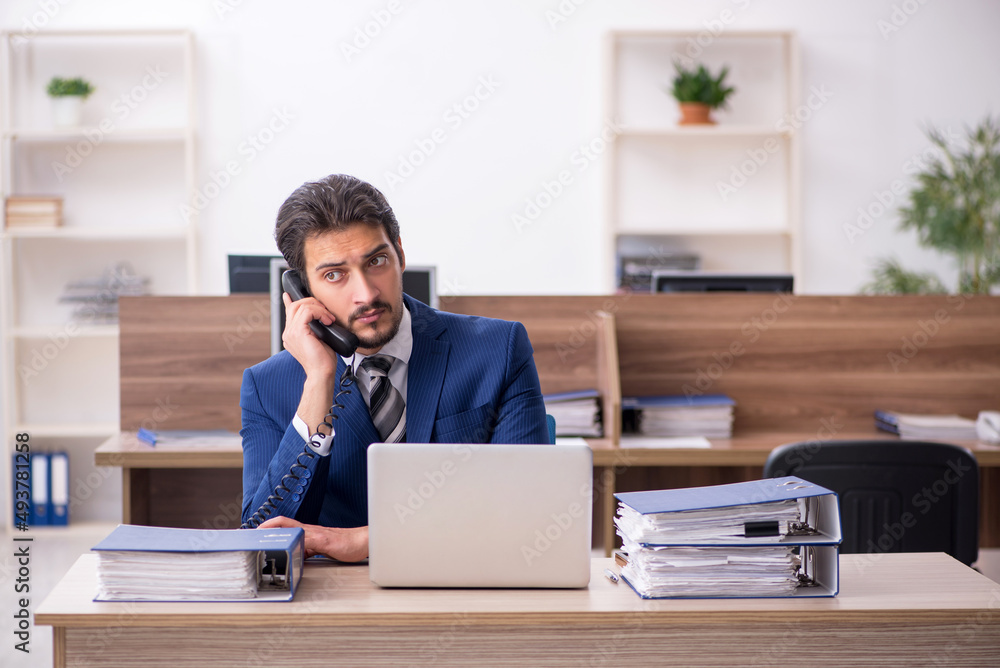Young male employee and too much work in the office Young male employee and too much work in the office