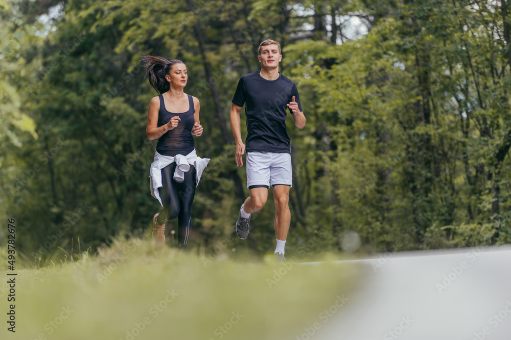 Young fit couple atheltes running on running road in a forest. Young fit couple atheltes running on running road in a forest.