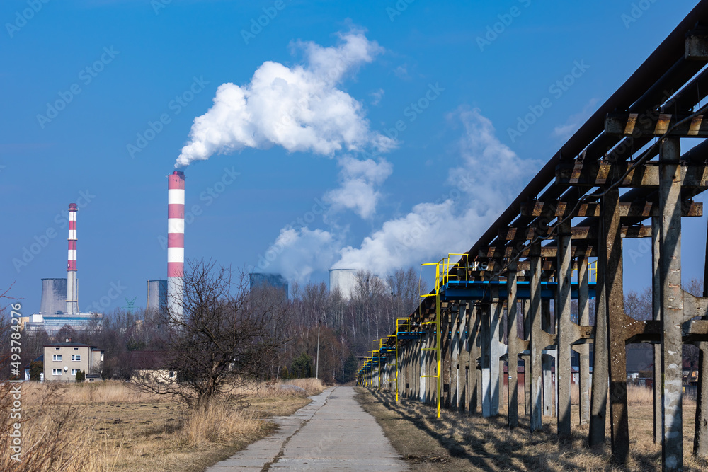Distant view of a coal-fired power plant. Smoking chimneys and steam from cooling towers. Photo taken on a sunny day, Contrast lighting.
