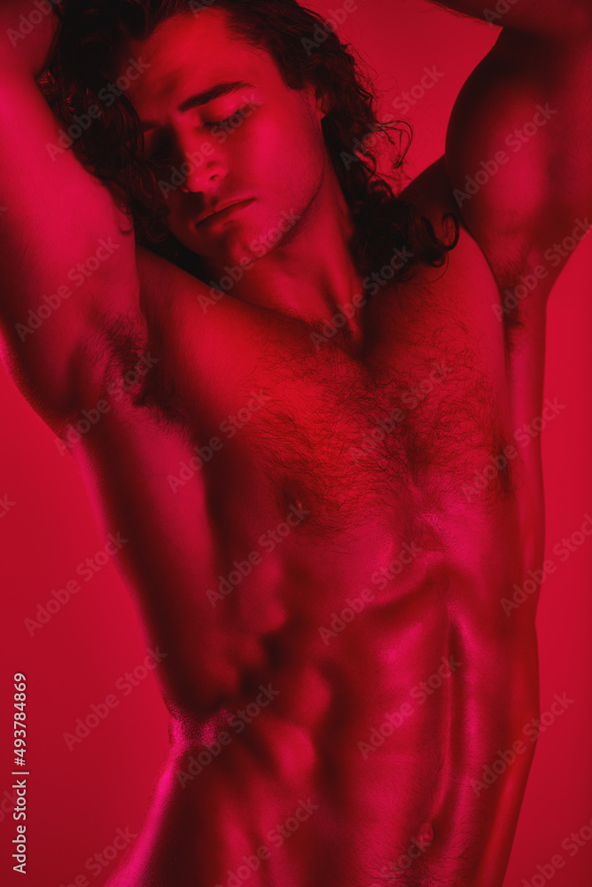 Breathtaking muscles. Studio shot of a muscular young man posing shirtless against a red background.