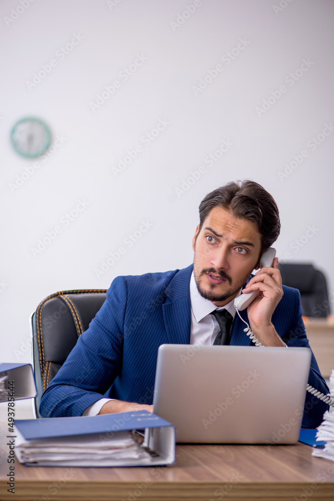 Young male employee and too much work in the office Young male employee and too much work in the office
