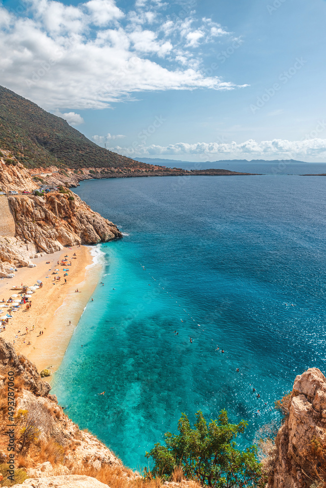 Naklejka premium Kaputas beach with blue water on the coast of Antalya region in Turkey with sun umbrellas on the beach