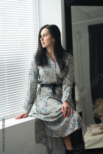 adult young woman is resting in a beautiful feminine blue dress in a bright room by the window relax rest break anticipation anticipation 