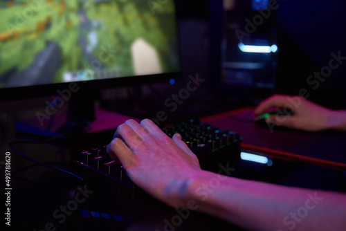 Professional gamer play computer video game in dark room  use neon colored rgb mechanical keyboard  place for cybersport gaming