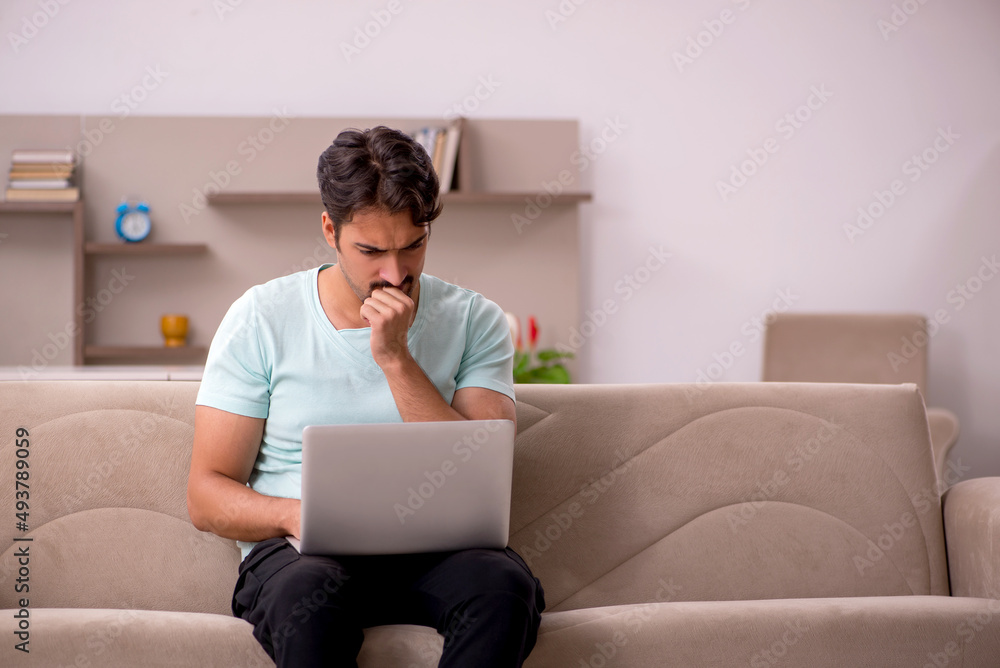 Young man sitting on the sofa with computer at home Young man sitting on the sofa with computer at home