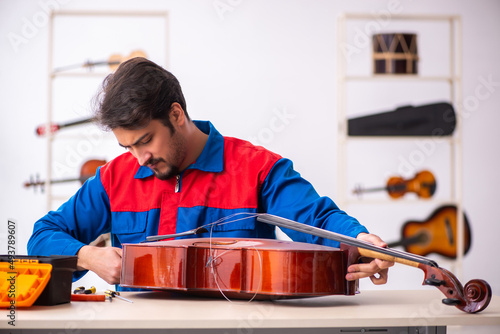 Obraz na plátně Young male repairman repairing musical instruments at workplace