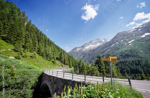 Yellow empty signboard with pointer. Asphalt road in Alps mountains. Trip concept.