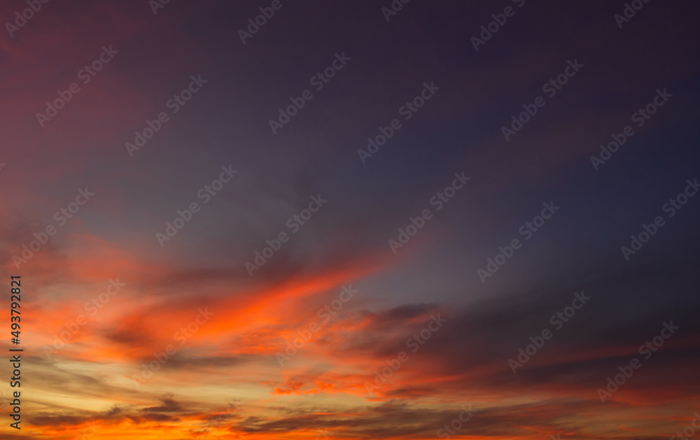 Dusk sky in the evening on twilight with purple, orange sunlight clouds on dramatic dark blue sky