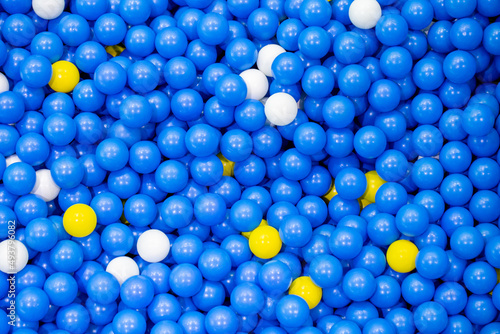 Blue, yellow and white plastic ballsin pool ball for background photo