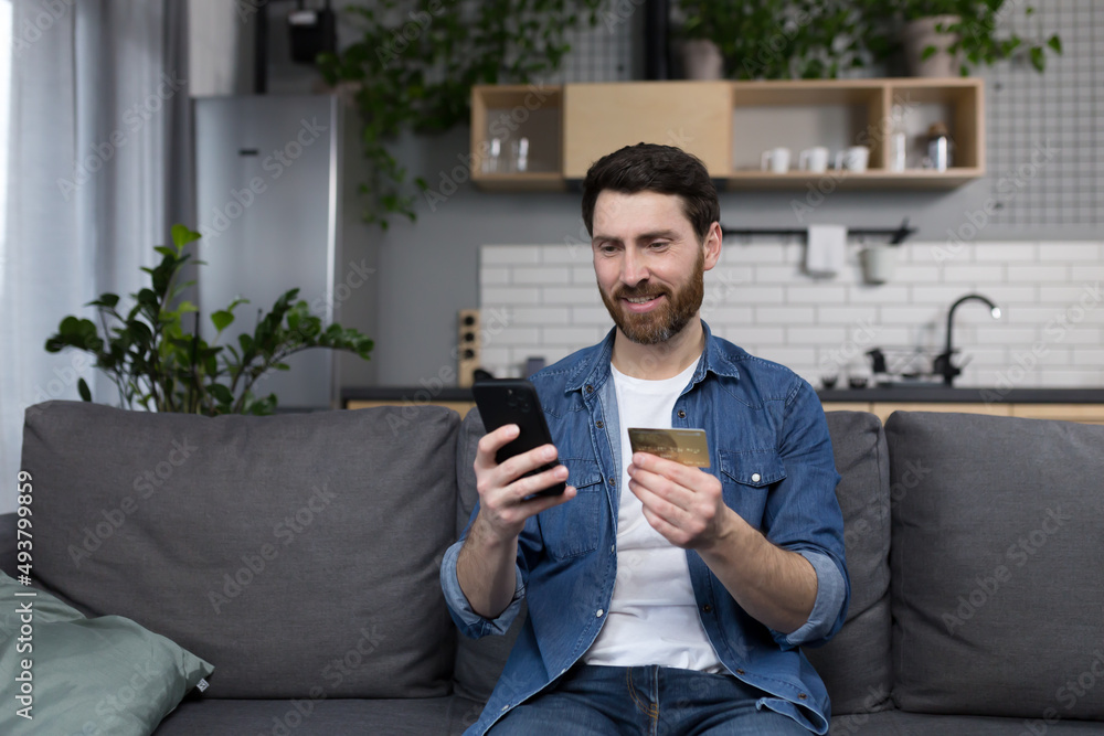 Freelancer at home performs banking operations, uses a banking application on a mobile phone, and a credit bank card Freelancer at home performs banking operations, uses a banking application on a mobile phone, and a credit bank card