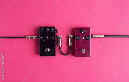 Two guitar pedals on a hot pink background. Guitar equipment. Flat lay, top view.  photo
