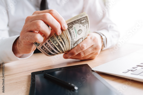 Businessman counting petty cash US dollar banknotes in office