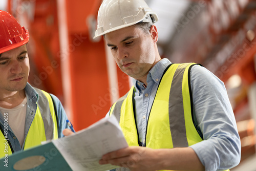 Engineer or foreman hard work with paperwork and machine at factory 