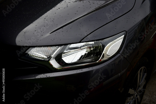 Bangkok Thailand August 03 2019 Resistant glass car headlights illuminate a black car with water droplets from rain.