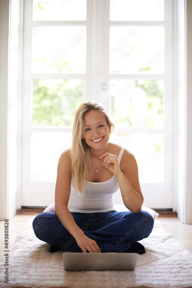 You can find anything online. Smiling young woman sitting on the floor and using her laptop.