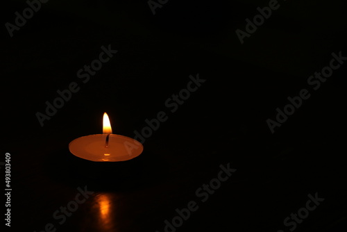 Single candle light burning in the dark place. For using in traditional activity and rite.