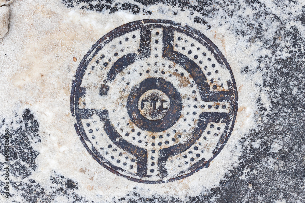 Manhole cover covered with snow