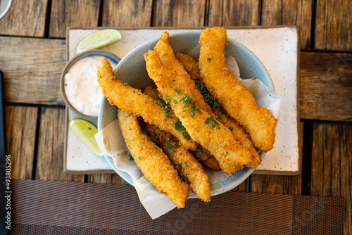 Fresh fried Brazilian tilapia fish strips with lime and tartar sauce known as isca de peixe. Traditional Brazilian appetizer. Selective focus