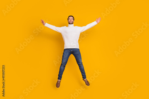 Photo of pretty attractive guy wear white pullover jumping high like star isolated yellow color background © deagreez